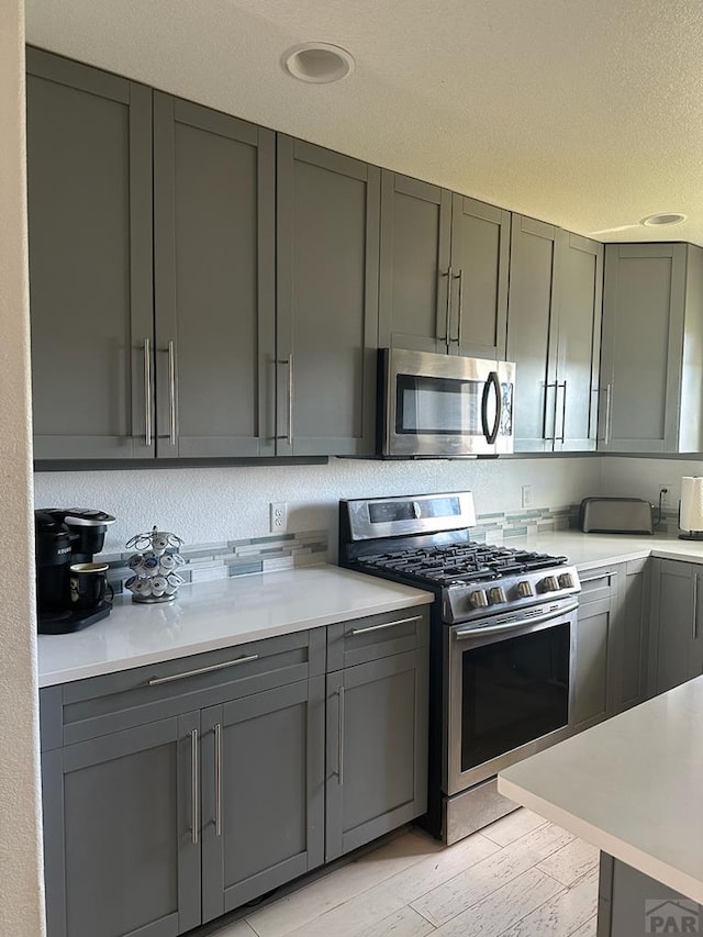 kitchen featuring tasteful backsplash, gray cabinets, appliances with stainless steel finishes, and light countertops