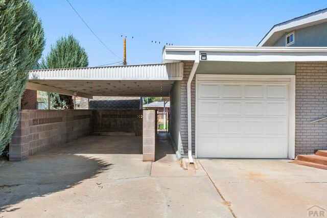 garage with a carport, fence, and concrete driveway