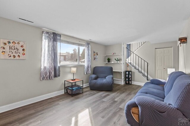 living area featuring stairway, wood finished floors, visible vents, and baseboards