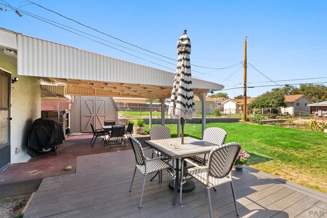 wooden deck featuring grilling area, a shed, outdoor dining area, and a yard