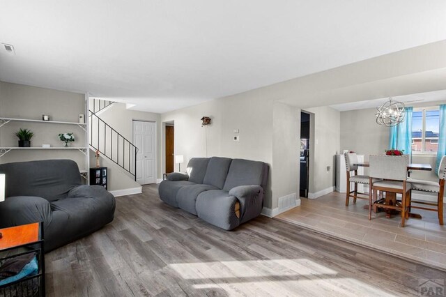 living room featuring wood finished floors, visible vents, baseboards, and stairs