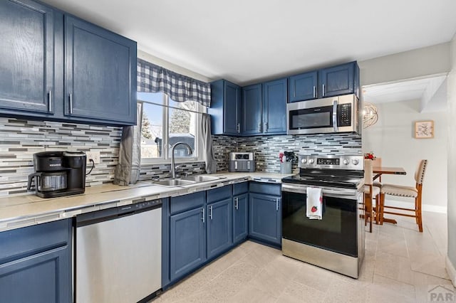 kitchen featuring light countertops, appliances with stainless steel finishes, a sink, and blue cabinets