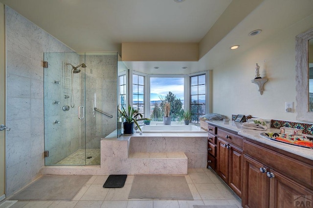 full bath featuring a stall shower, tile patterned flooring, a garden tub, and vanity