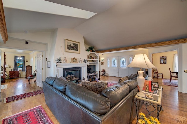 living room featuring a glass covered fireplace, lofted ceiling, and light wood finished floors