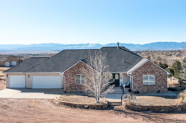 ranch-style home featuring a garage, concrete driveway, brick siding, and a mountain view