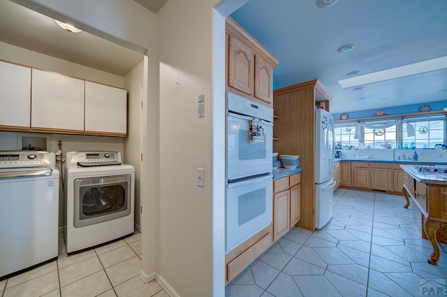 kitchen featuring light countertops, white appliances, independent washer and dryer, and light brown cabinetry