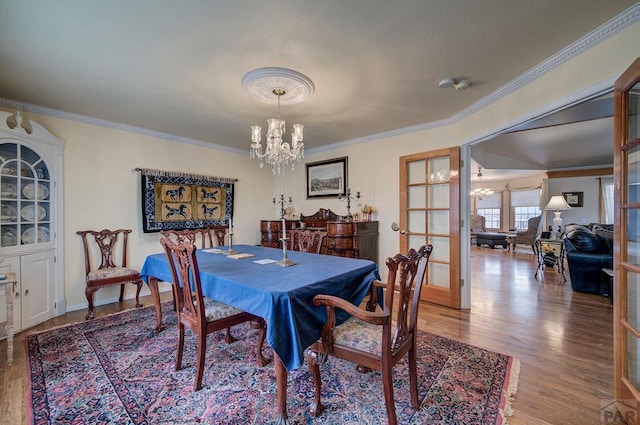 dining space featuring baseboards, ornamental molding, light wood-style flooring, and an inviting chandelier