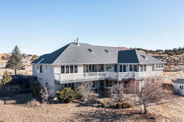 back of house featuring a deck, a shingled roof, and stucco siding