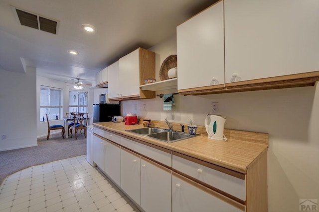 kitchen with open shelves, light countertops, visible vents, white cabinetry, and a sink