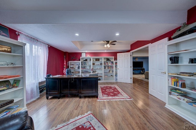 office space featuring ceiling fan, a tray ceiling, wood finished floors, and recessed lighting