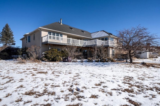 snow covered rear of property with a balcony