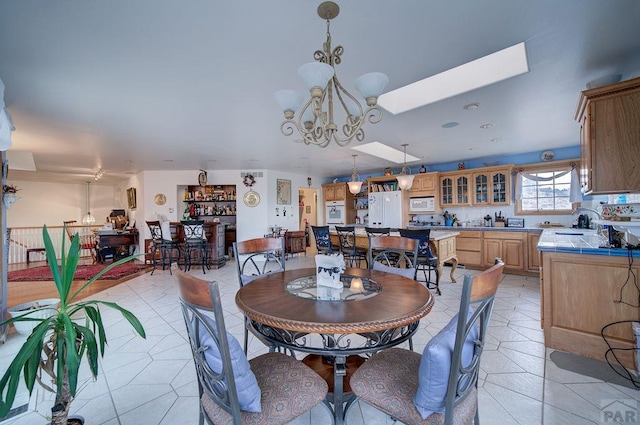 dining space featuring a skylight, light tile patterned floors, and a notable chandelier