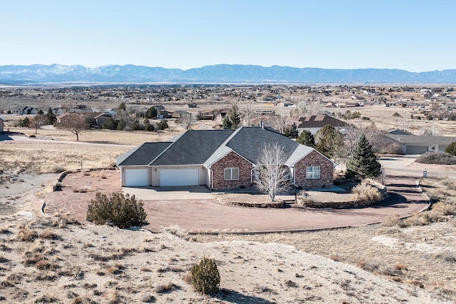 view of front of house featuring driveway, an attached garage, a mountain view, a desert view, and brick siding