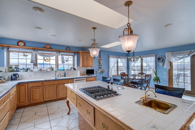 kitchen with tile countertops, appliances with stainless steel finishes, a kitchen island, and a sink