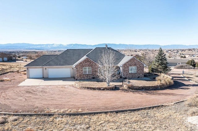 ranch-style home with driveway, an attached garage, and a mountain view