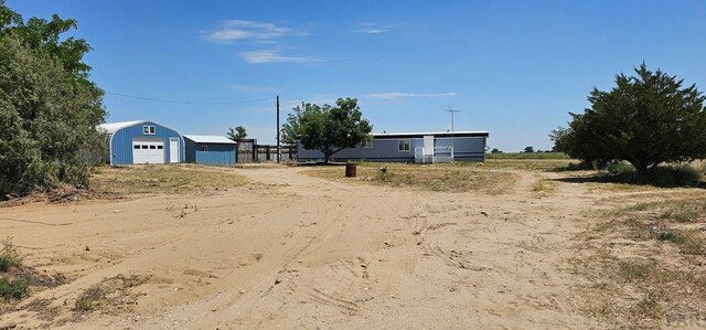 view of yard with a garage, an outbuilding, and driveway