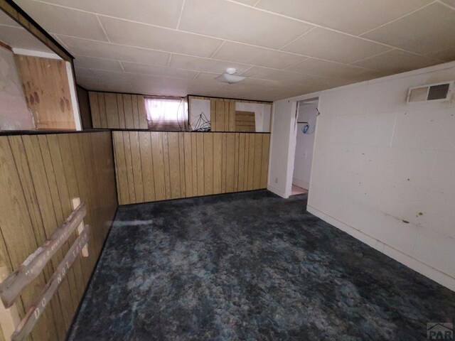 finished basement featuring concrete block wall, wood walls, and visible vents