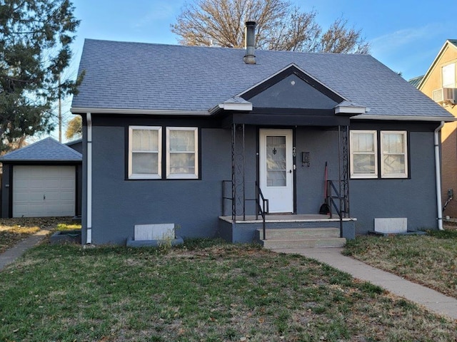 bungalow-style house with a shingled roof, a front yard, an outdoor structure, and stucco siding