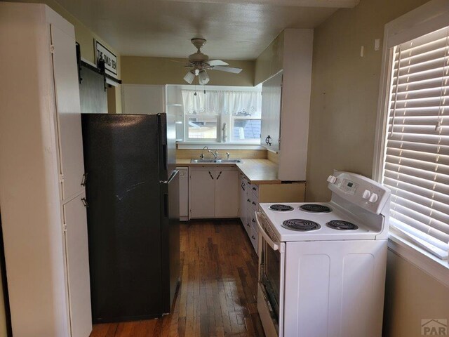 kitchen featuring white range with electric cooktop, light countertops, freestanding refrigerator, white cabinetry, and a sink