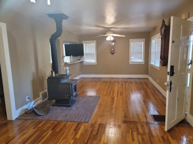 interior space featuring a wood stove, a healthy amount of sunlight, baseboards, and wood finished floors