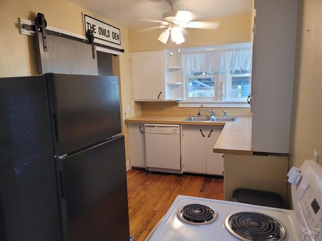 kitchen with a barn door, dishwasher, freestanding refrigerator, light countertops, and white cabinetry