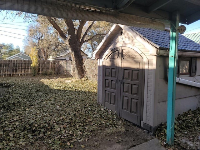 exterior space with a storage shed, an outbuilding, and fence