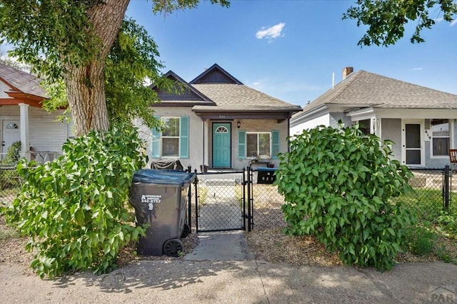 view of front of home featuring a gate, a chimney, fence private yard, a shingled roof, and stucco siding