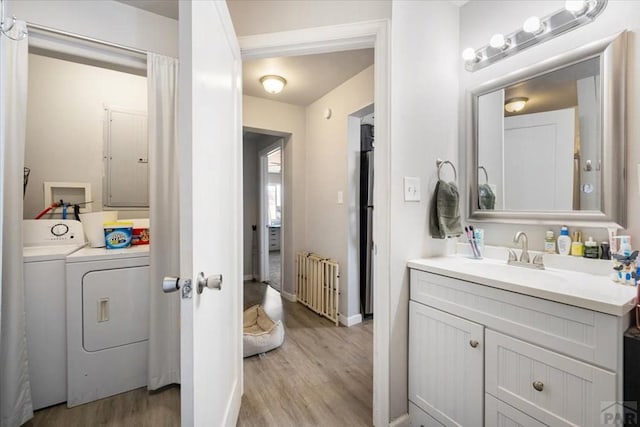 bathroom with washer and clothes dryer, baseboards, radiator heating unit, wood finished floors, and vanity