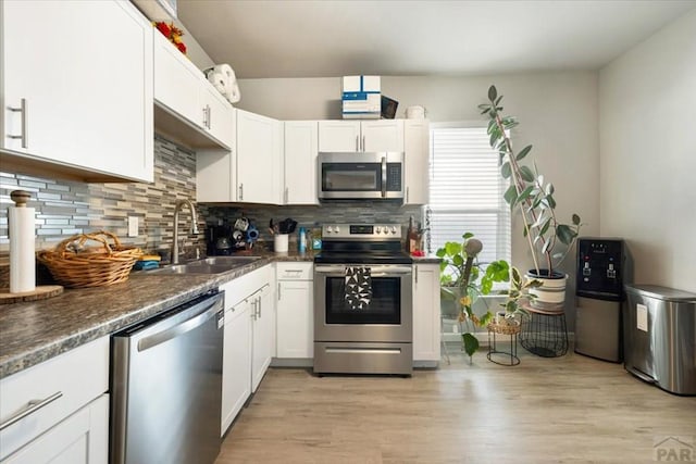 kitchen with backsplash, a sink, white cabinetry, and appliances with stainless steel finishes