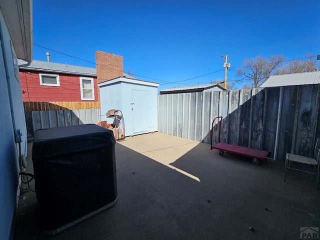 view of patio / terrace featuring a storage unit, an outdoor structure, and fence