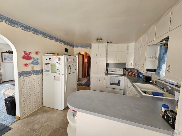 kitchen featuring white appliances, a peninsula, arched walkways, a sink, and tile patterned floors