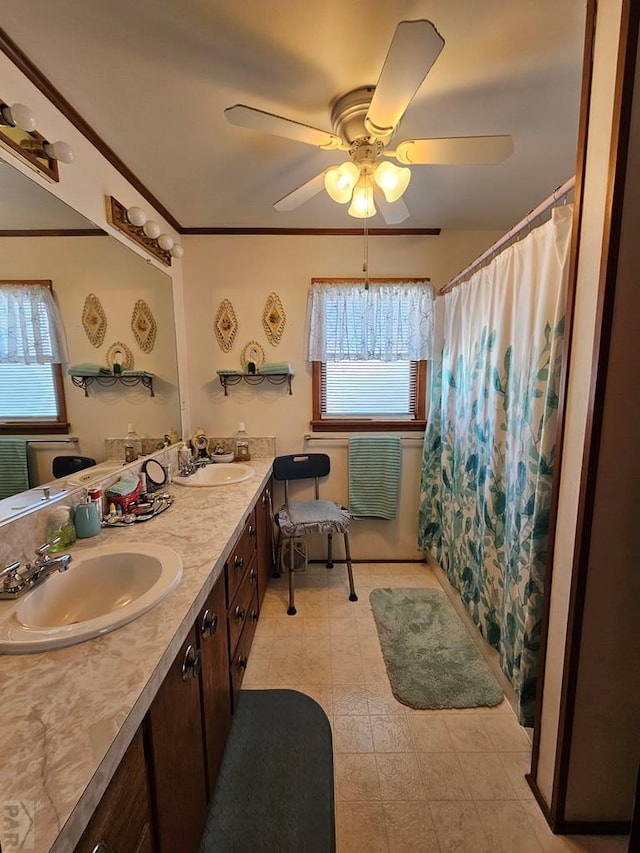 full bath with a sink, ceiling fan, double vanity, and crown molding