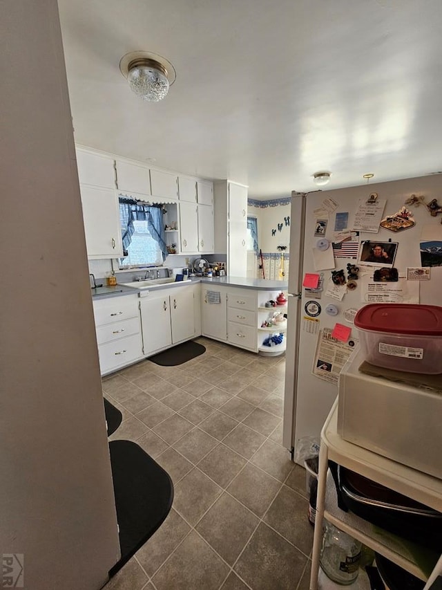 kitchen with tile patterned floors, open shelves, white cabinetry, and freestanding refrigerator