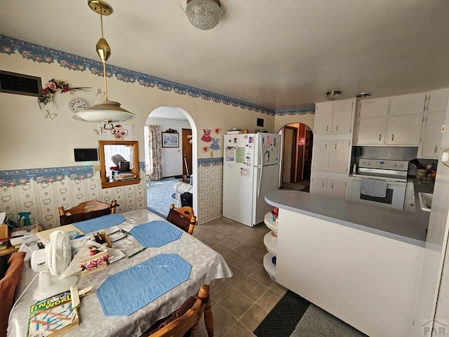 dining area with arched walkways, dark tile patterned floors, and wallpapered walls