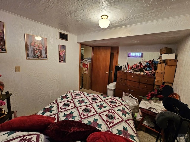 bedroom featuring visible vents, a textured ceiling, and a textured wall