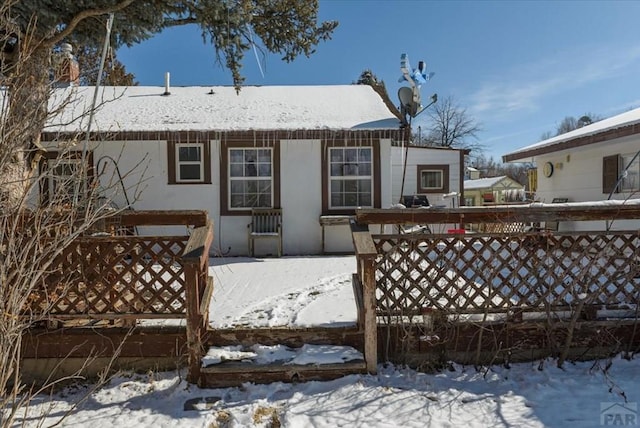 snow covered property with stucco siding