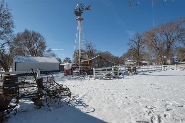 snow covered rear of property featuring fence and an outbuilding