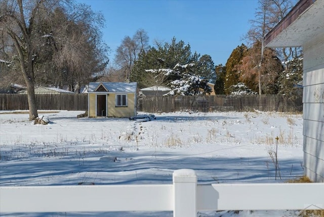 snowy yard featuring fence and an outbuilding