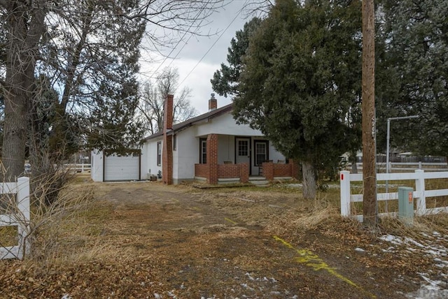 view of side of home featuring brick siding, fence, a chimney, and an attached garage