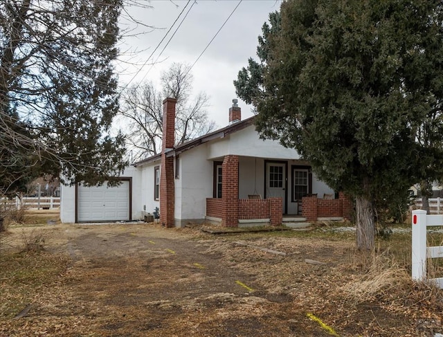 view of front of home featuring an attached garage, driveway, a chimney, and brick siding