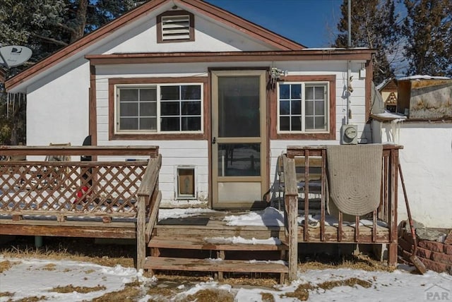 snow covered house with a wooden deck