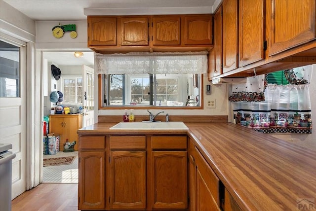 kitchen featuring brown cabinetry, light wood-type flooring, butcher block counters, and a sink