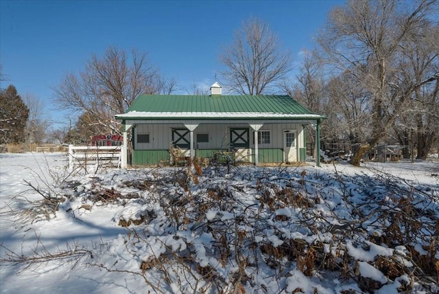 view of front facade with a chimney, metal roof, and board and batten siding