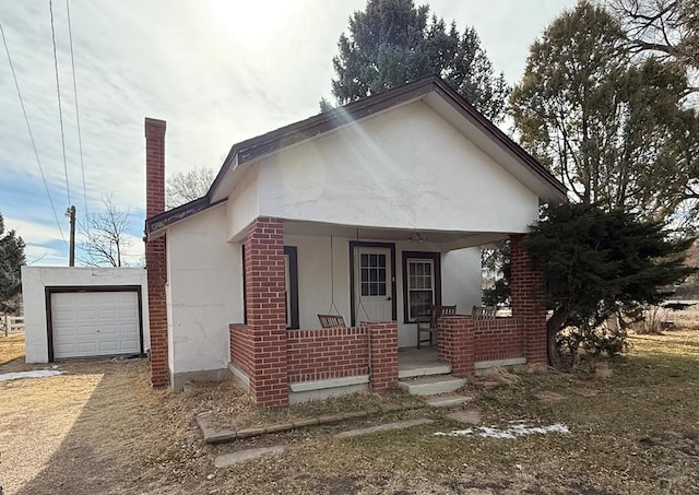 view of front facade featuring a porch, brick siding, an attached garage, and stucco siding