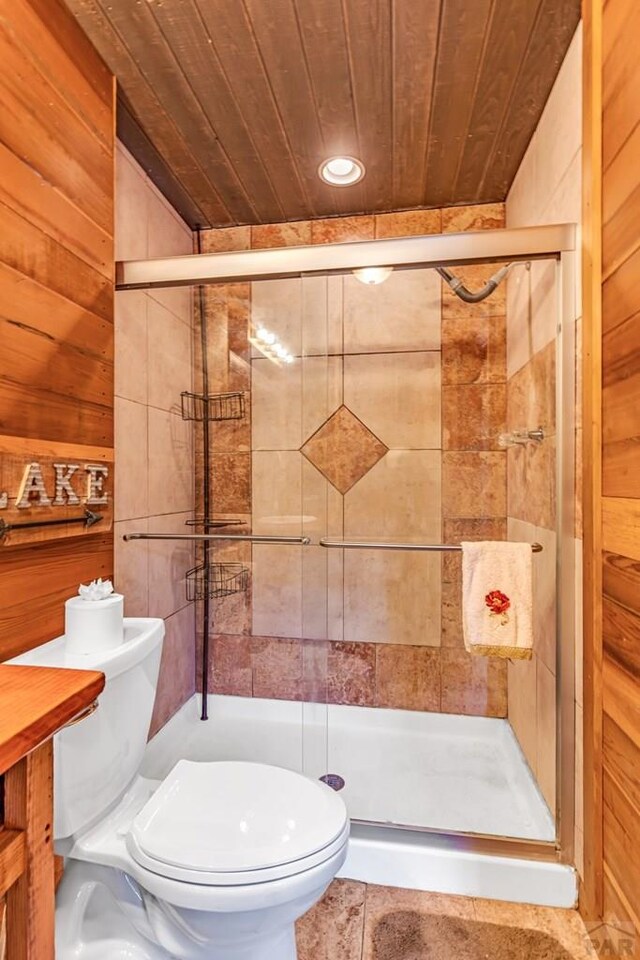 full bath with wood walls, wooden ceiling, toilet, and a stall shower