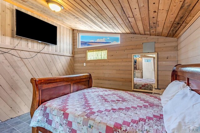 tiled bedroom featuring vaulted ceiling, wooden ceiling, and wood walls