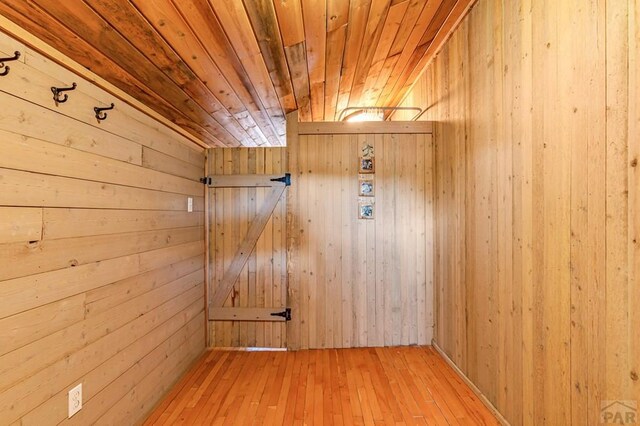 doorway to outside with wood walls, wooden ceiling, and wood finished floors