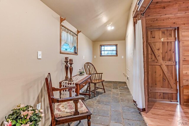 living area with lofted ceiling and stone tile floors