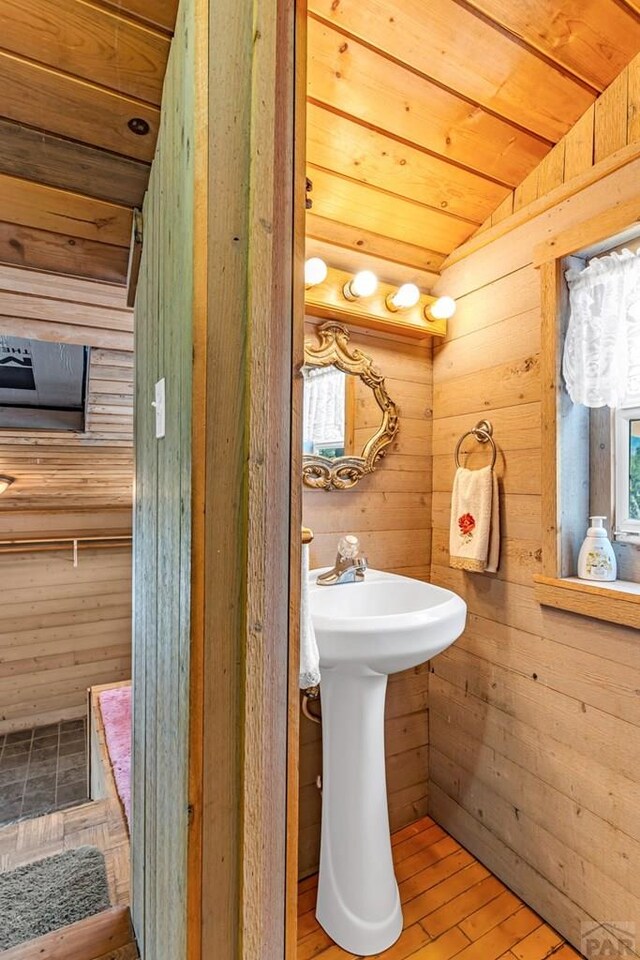 bathroom with wooden ceiling, vaulted ceiling, wooden walls, and wood finished floors