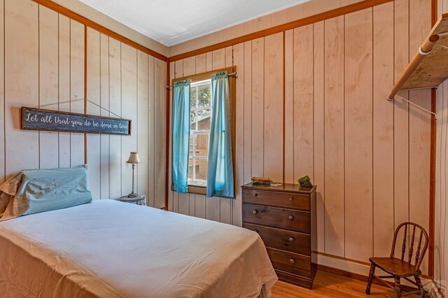 bedroom with wood walls and light wood-style floors